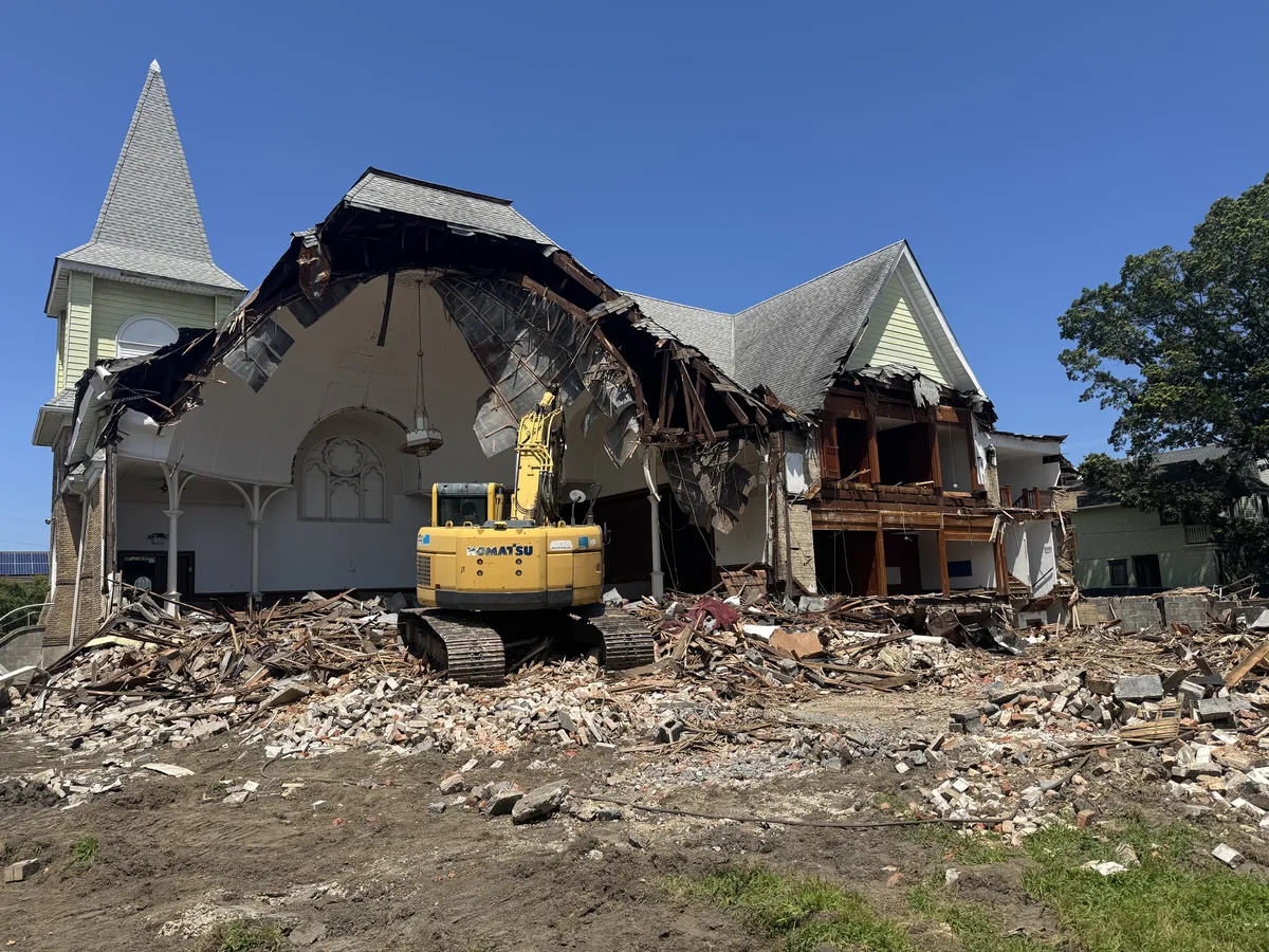 Church with its roof torn open behind the steeple and an excavator in the opening