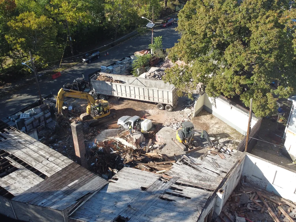Aerial view of the loaded debris trailer pulled out onto the street beside the teardown lot