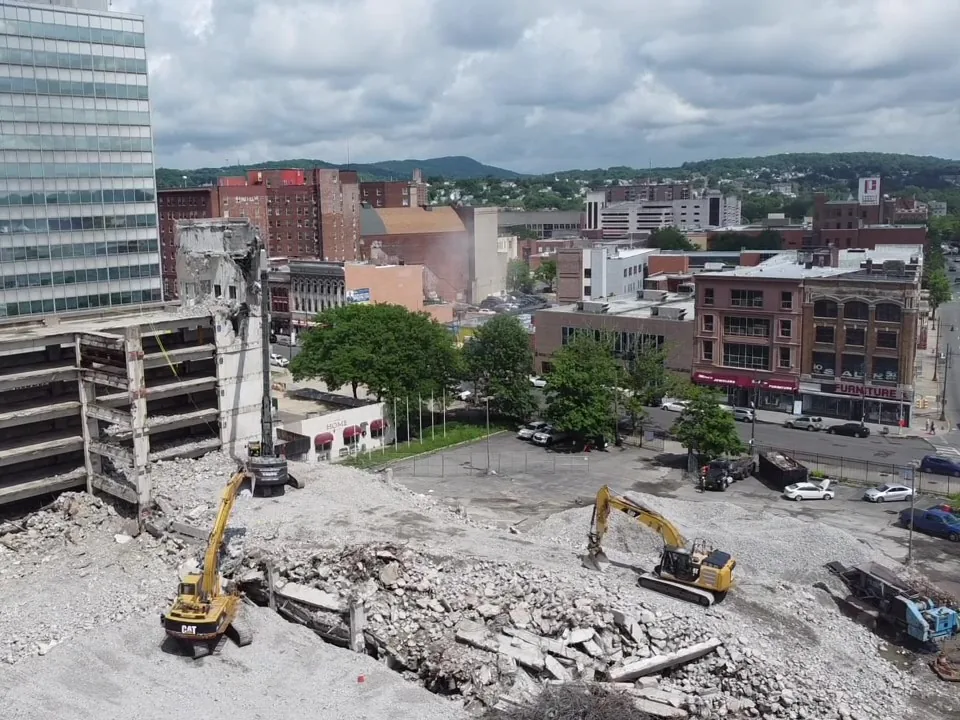 Aerial view of excavators on broken concrete from a parking structure teardown with a crusher working the rubble, industrial demolition